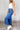 Side view of model wearing the Ceros: Florence Medium Wash Wide Leg Jeans which features medium blue denim fabric, a front zipper with a button closure, belt loops, a super high-rise waist, two front pockets, two back pockets, and wide cropped legs with d