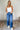 FUll body view of model wearing the Ceros: Florence Medium Wash Wide Leg Jeans which features medium blue denim fabric, a front zipper with a button closure, belt loops, a super high-rise waist, two front pockets, two back pockets, and wide cropped legs w
