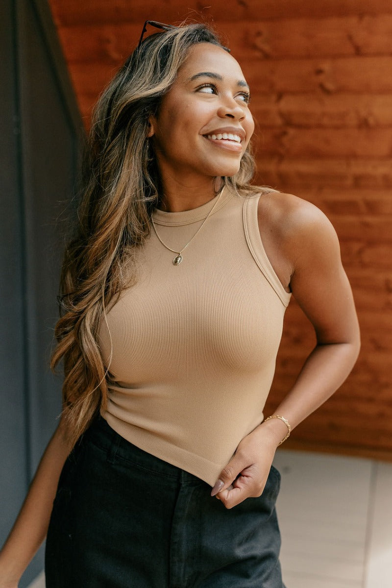 Front view of model wearing the Payton Tan Ribbed Sleeveless Tank which features tan ribbed fabric, thick hem, round neckline and sleeveless.