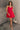 Full body view of model wearing the Avery Red Bow Mini Dress which features crimson red sheen fabric, red lining, mini length, two front pockets, sweetheart neckline, adjustable straps, sleeveless, monochromatic side zipper with hook closure, smocked back