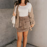 Full body view of model wearing the Journey Mocha Brown Cargo Mini Skirt which features taupe brown textured soft fabric, two fornt cargo pocket with zipper closure, elastic waistband with tie and mini length.