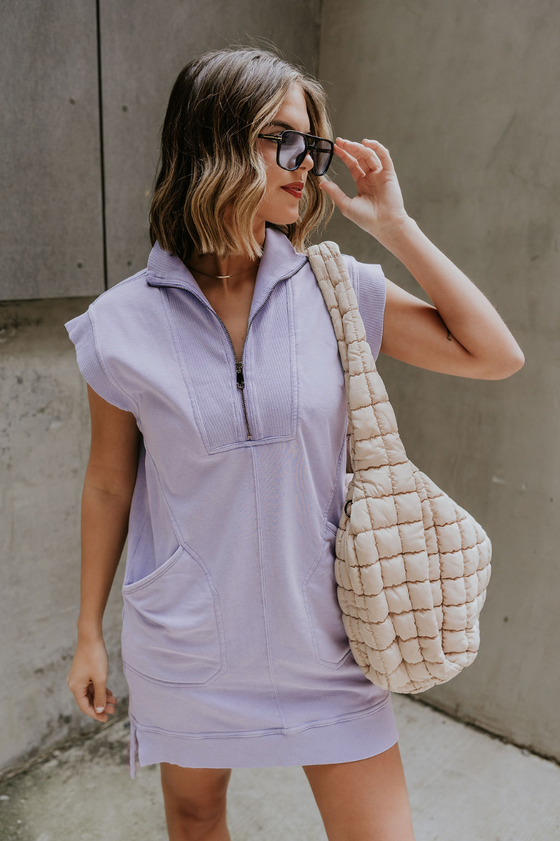 Front view of model wearing the Lottie Periwinkle Quarter-Zip Sleeveless Mini Dress which features light periwinkle knit fabric, ribbed details, two front pockets, mini length, small slits on each side, quarter zip up with high neckline and sleeveless.