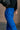 Upper side view of model wearing the Kyla Royal Parachute Cargo Pants that have dark royal breathable nylon fabric, pockets, an elastic waist with a bungee, and relaxed legs with elastic ankles and bungees.