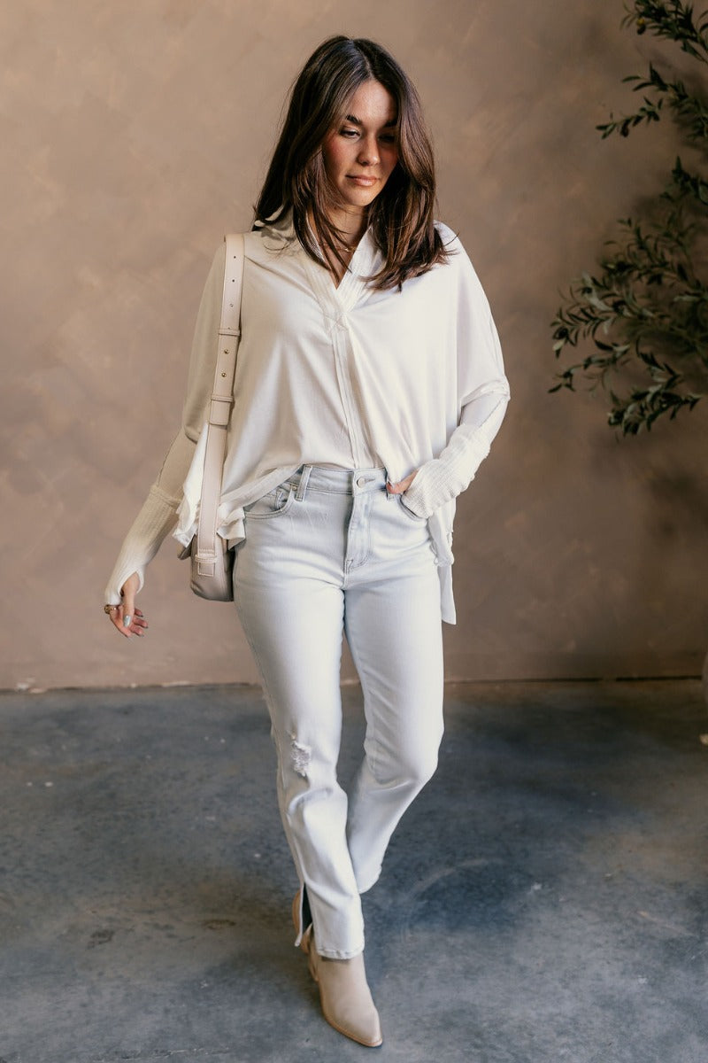 Full body view of model wearing the Karlee White Collared Long Sleeve Top which features off white knit fabric, high-low hem, slight slits on each side, waffle knit textured details, v-neckline with collar and long sleeves with cuffs.