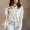 Front view of model wearing the Karlee White Collared Long Sleeve Top which features off white knit fabric, high-low hem, slight slits on each side, waffle knit textured details, v-neckline with collar and long sleeves with cuffs.