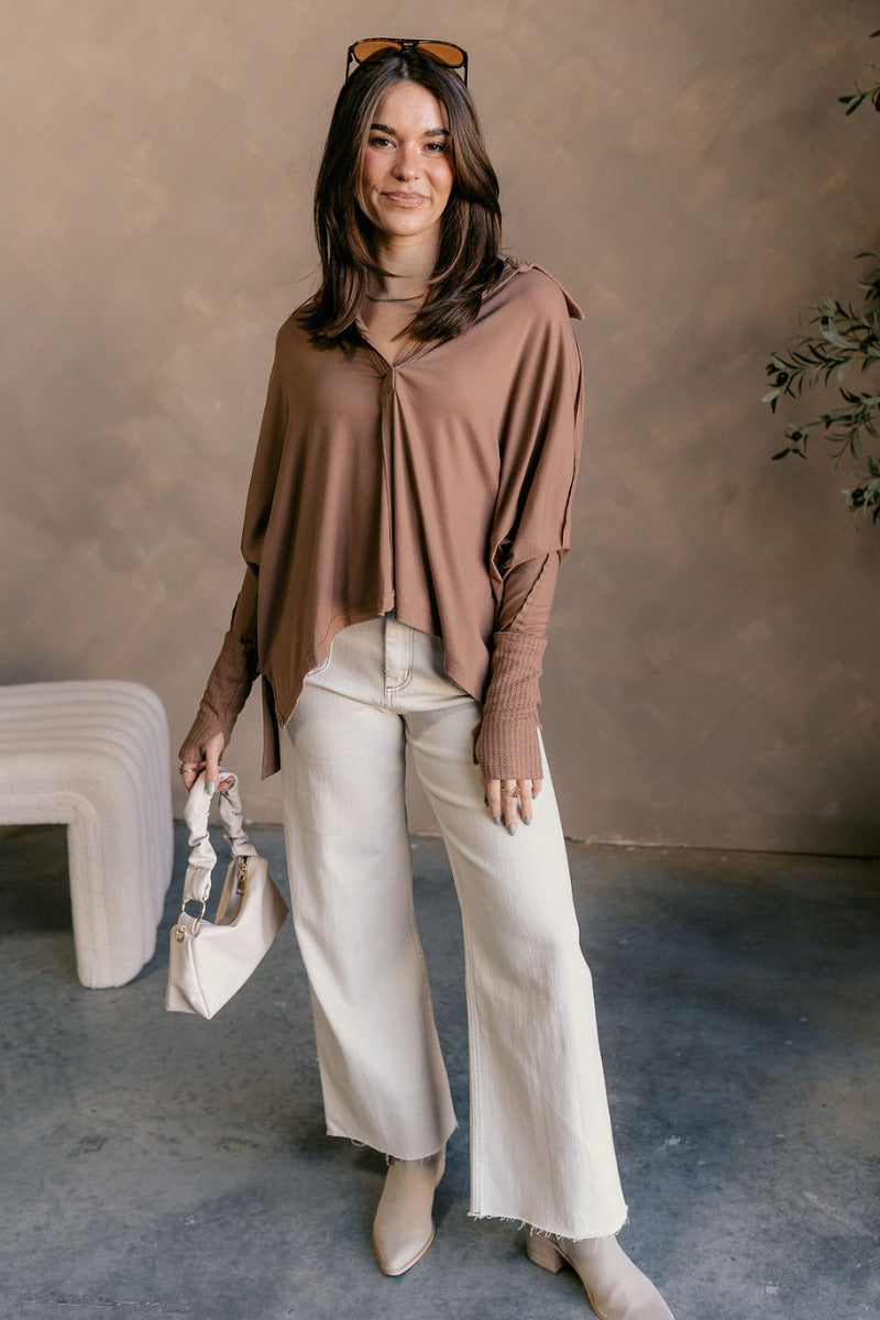 Full body view of model wearing the Karlee Mocha Collared Long Sleeve Top which features mocha knit fabric, a high-low hem, slight slits on each side, waffle knit textured details, a v-neckline with a collar, and long sleeves with cuffs.