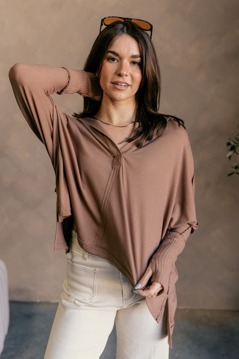 Front view of model wearing the Karlee Mocha Collared Long Sleeve Top which features mocha knit fabric, a high-low hem, slight slits on each side, waffle knit textured details, a v-neckline with a collar, and long sleeves with cuffs.