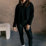 Full body view of model wearing the Nicole Black Cropped Long Sleeve Top which features black cotton fabric, a cropped waist, a round neckline, and long sleeves.