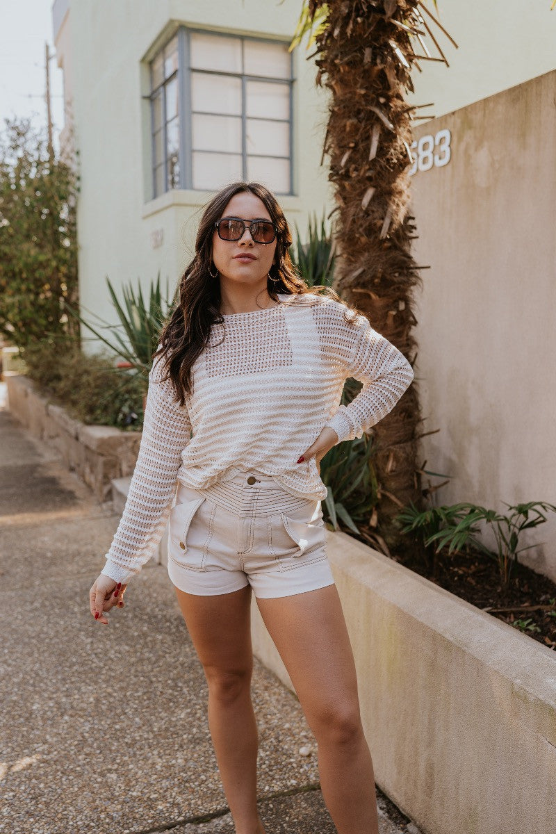 Full body view of the Capri Knit Top which features white and tan open knit fabric, striped pattern, round neckline and long sleeves.