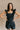 Front view of model wearing the Avril Black Denim Ruffle Sleeveless Romper which features black washed denim fabric, pockets on each side, a front zip up, an elastic waistband, a square neckline, and ruffle straps.