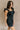 Front side view of model wearing the Avril Black Denim Ruffle Sleeveless Romper which features black washed denim fabric, pockets on each side, a front zip up, an elastic waistband, a square neckline, and ruffle straps.