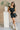 Full body view of model wearing the Avril Black Denim Ruffle Sleeveless Romper which features black washed denim fabric, pockets on each side, a front zip up, an elastic waistband, a square neckline, and ruffle straps.