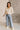 Front view of model wearing the Ceros: Florence Light Wash Wide Leg Jeans that have light denim wash fabric, pockets, a front zipper,  belt loops, super high waisted, wide cropped flares and distressed hem.