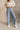 Front view of model wearing the Ceros: Florence Light Wash Wide Leg Jeans that have light denim wash fabric, pockets, a front zipper,  belt loops, super high waisted, wide cropped flares and distressed hem.