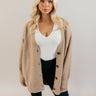 front view of model wearing the Oaklynn Mocha Oversized Cardigan that has mocha brown knit fabric, ribbed hem, a button-up front with dark tortoise buttons, a v-neckline, and long sleeves with cuffs.