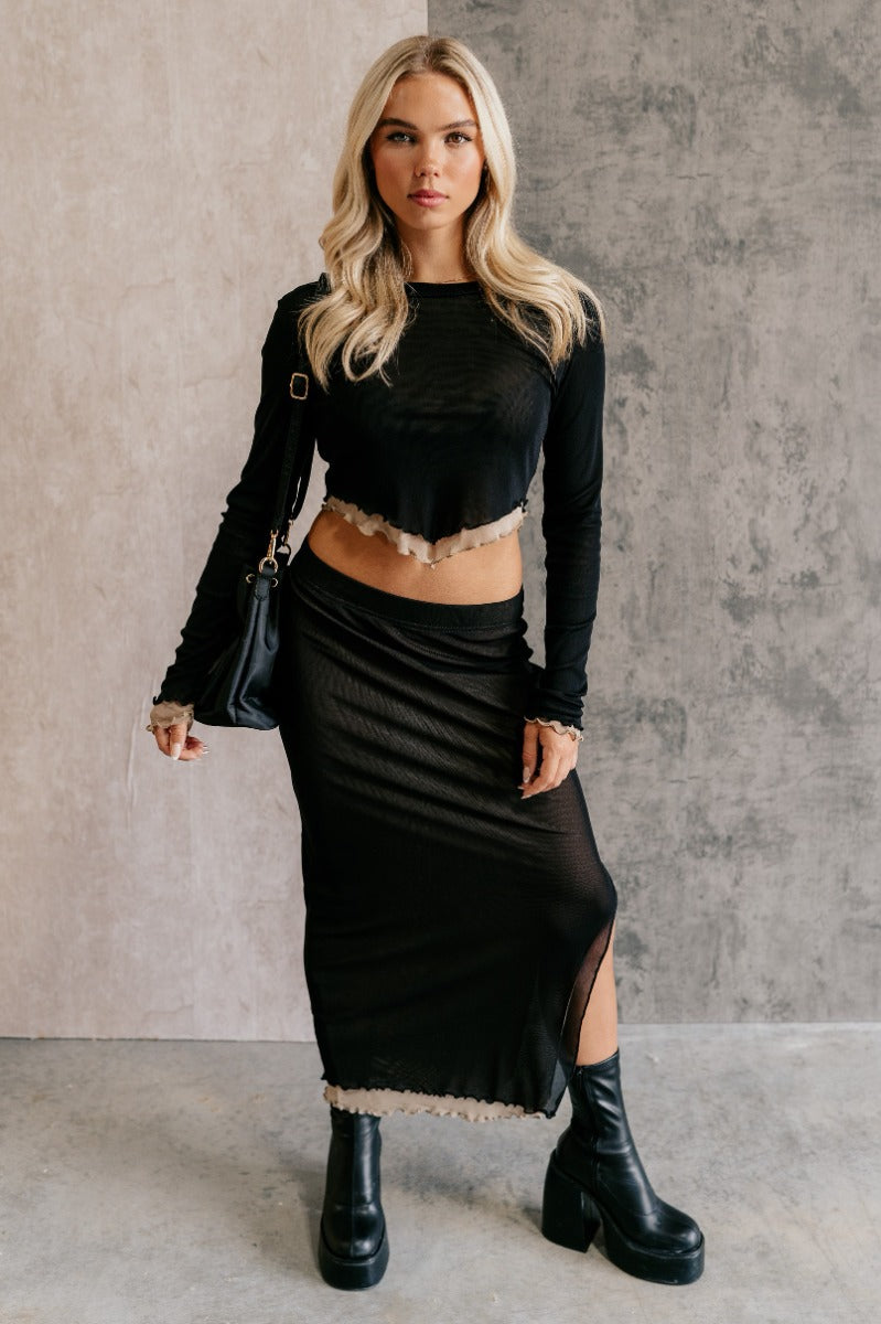 Full body front view of model wearing the Kylie Black & Taupe Mesh Midi Skirt that has black mesh fabric, taupe mesh lining, an elastic waist, a slit on the side, and lettuce hem details.