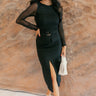 Full body front view of model wearing the Hailey Belted Black Front-Slit Midi Skirt that has black lightweight fabric, cargo pockets, a side zipper with a hook, a shiny gold hoop belt detail, midi length, and a front slit.