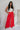 Full body view of model wearing the Scarlett Red Wide Leg Pants which features red lightweight fabric, two front pockets, a front zipper with a hook closure, belt loops and wide legs.