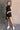 Full body view of model wearing the Emily Washed Black Denim Sleeveless Romper which features washed black denim fabric, two front pockets, silver button details, button up front closure, two front chest buttoned pockets, two back pockets, collared neckli
