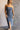 Front view of model wearing the Carrie Washed Denim Slit Strapless Midi Dress which features medium denim wash fabric, brown stitch details, front slit detail, midi length, two front slit pockets, two back pockets, belt loops, frayed hem, straight across 