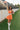 full body view of female model wearing the Amaya Strapless Flare Mini Dress in Orange which features Lightweight Fabric, Side Zipper Closure, Belt Loops, Two Front Pockets, Strapless and Shorts Lining.  Worn with white belt