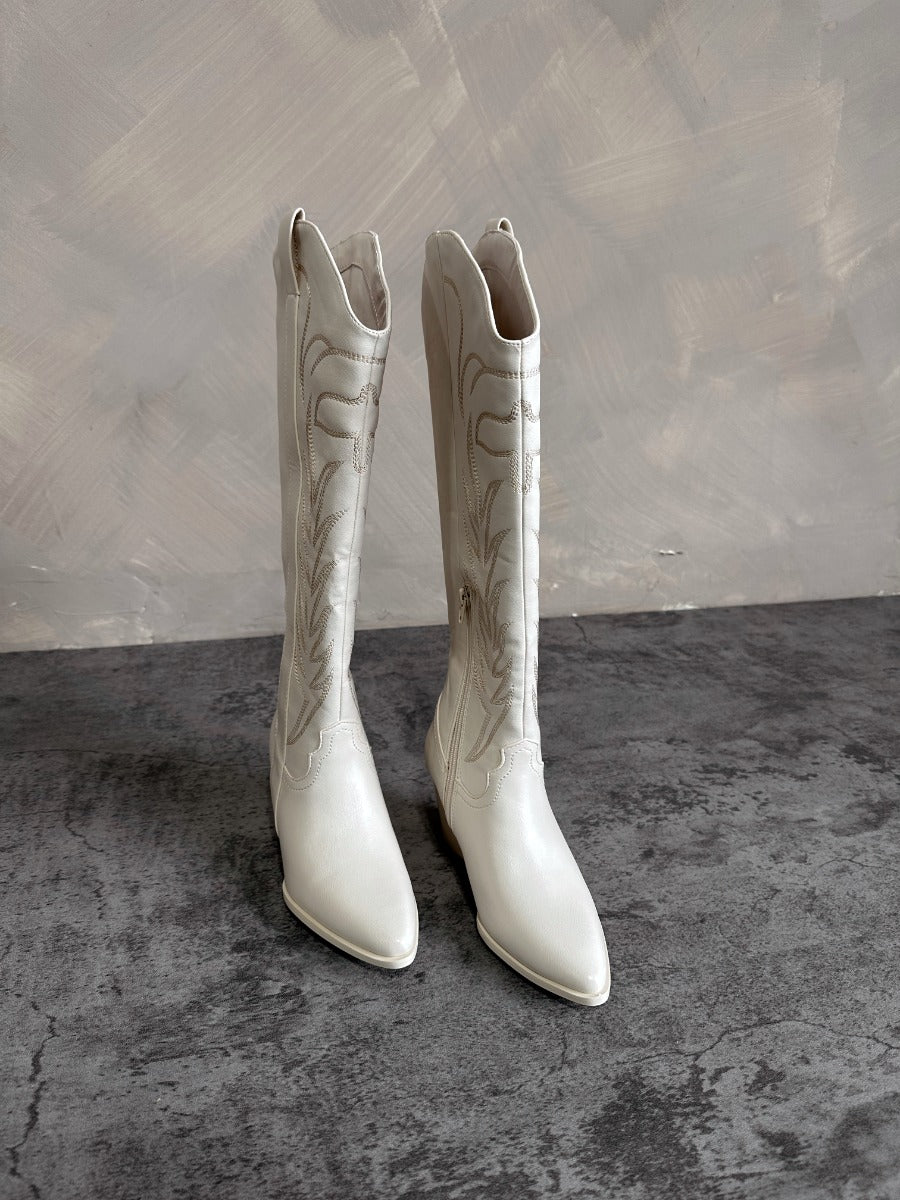 Front view of the Sierra Cream Western Boots that feature cream faux-leather with monochromatic western stitching, inner zipper closures, pointed toes, and 2.5" cream heels.