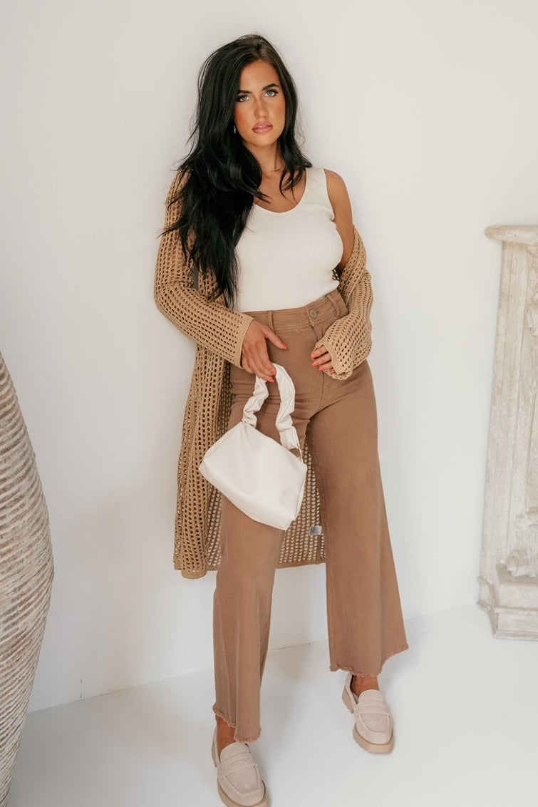Full body view of the female model wearing the Elias Flat in Dune Suede which features tan suede upper fabric, monochrome rubber sole, slide-on style and slight square toe design.