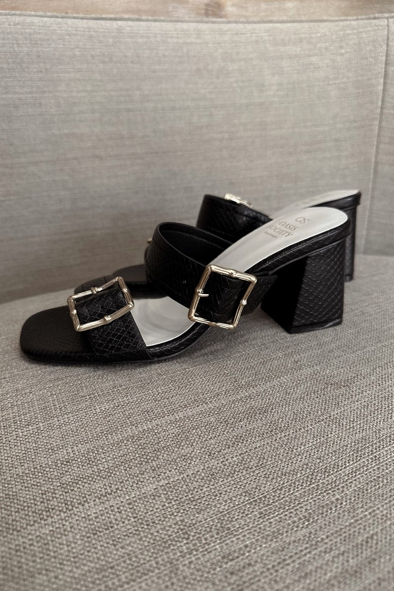 Side view of the Havana Black Heeled Sandals that have black snakeskin faux-leather material, two straps with adjustable gold buckles, square toes, and 2.5" block heels.