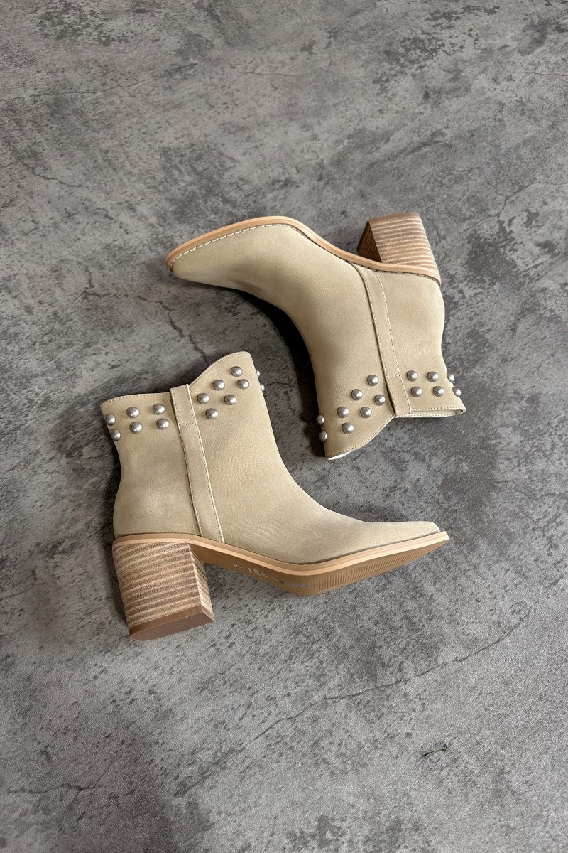 Aerial side view of the Alofi Taupe Studded Ankle Boots that feature taupe faux-leather, silver stud details, pointed toes, and 3" heels.