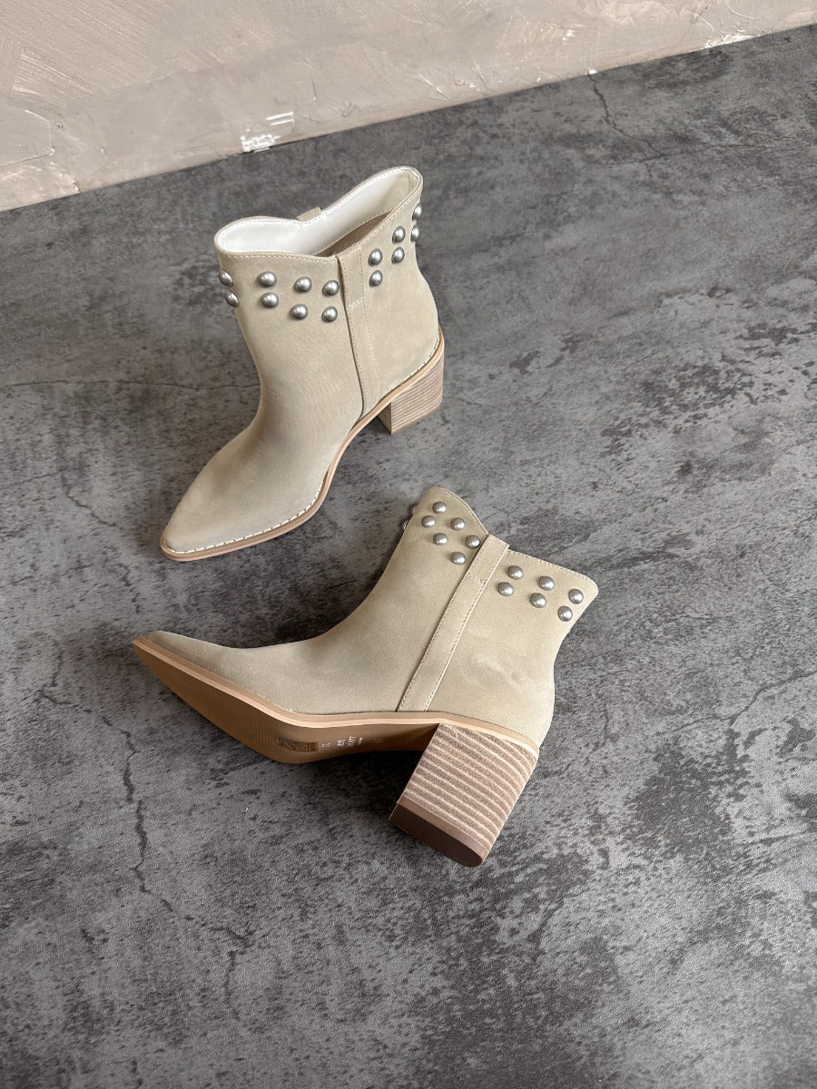 Aerial top and side view of the Alofi Taupe Studded Ankle Boots that feature taupe faux-leather, silver stud details, pointed toes, and 3" heels.