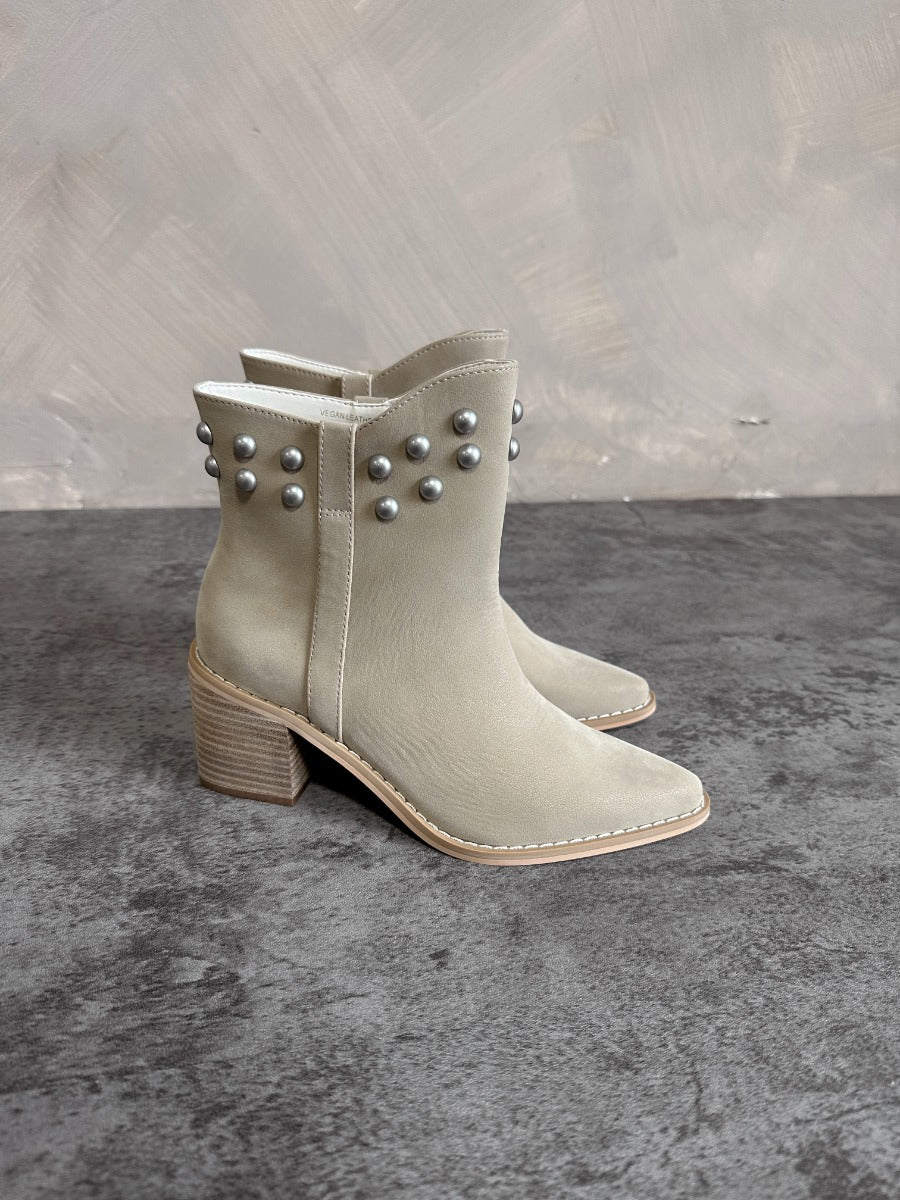 Side view of the Alofi Taupe Studded Ankle Boots that feature taupe faux-leather, silver stud details, pointed toes, and 3" heels.