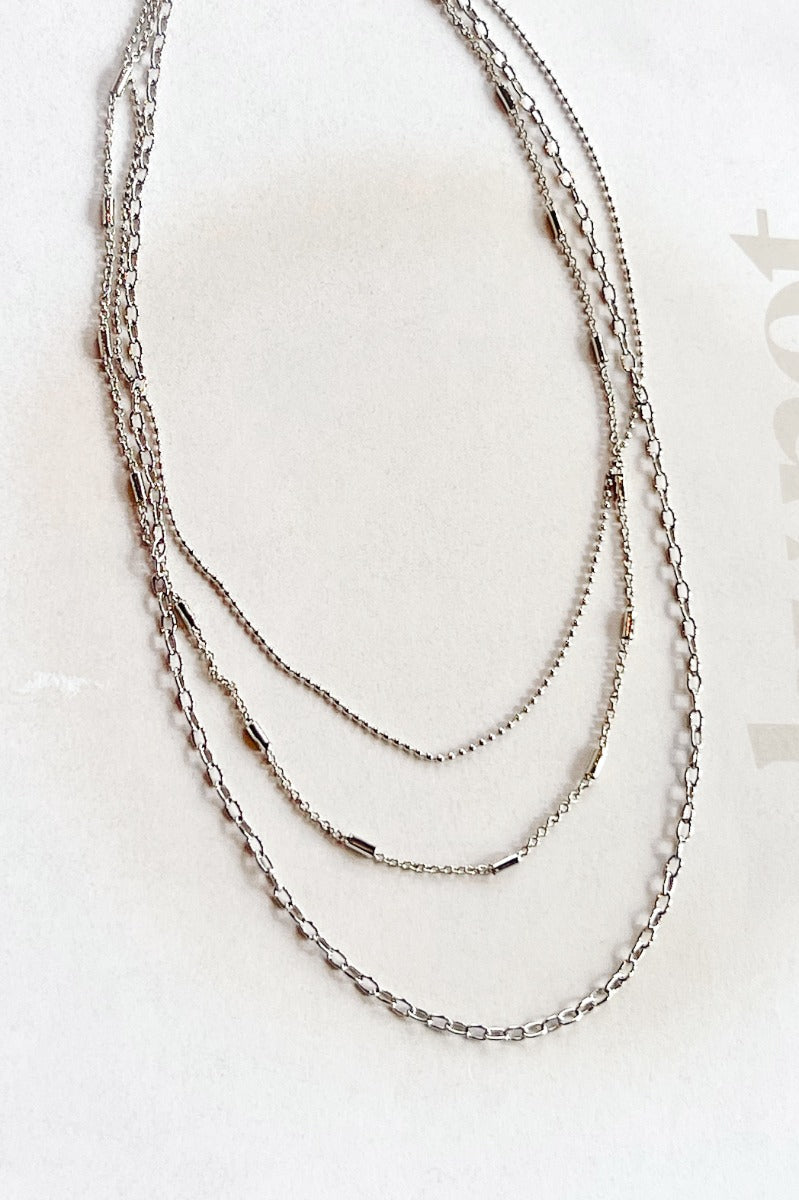 Aerial view of the Own It Necklace, that features three varied silver chains.