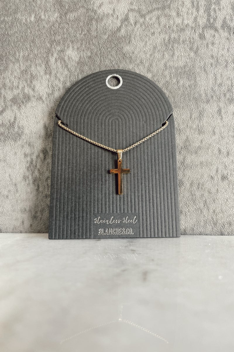 Front view of the Andrea Gold Cross Necklace that has a gold chain with a cross pendant and an adjustable clasp closure, shown against a black earring card.