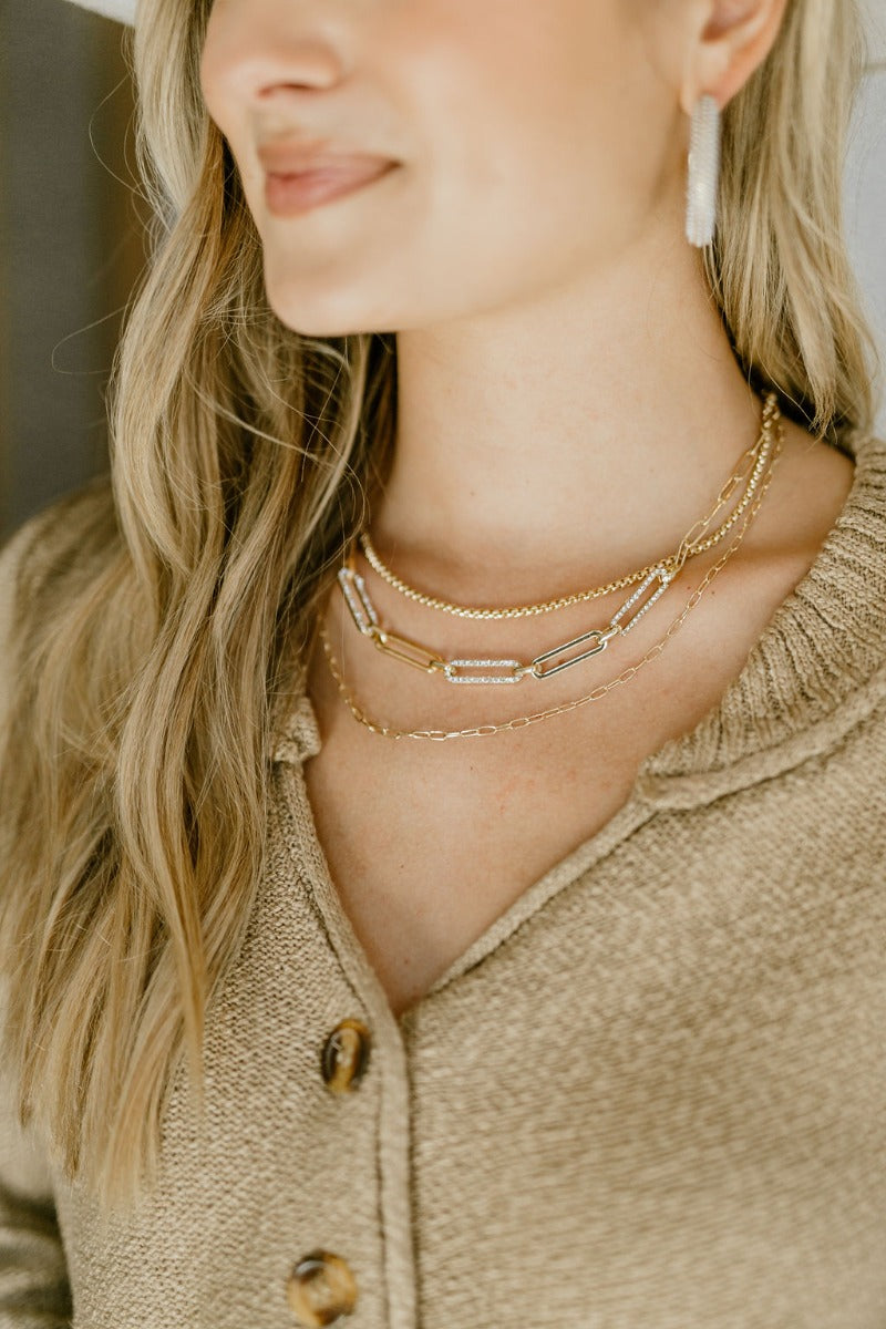 Front view of model wearing the Cheerful Spirits Necklace which features triple chain link with large chain links in clear stones.
