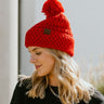 Close side view of model wearing the Fireside Beanie in Pink that has pink knit fabric, a folded cuff with a brown "C.C" patch, and a pink pompom.
