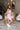 Side view of model wearing the Out And About Dress In Lavender which features lavender knit fabric, ruched side details, midi length, lavender lining, a round neckline and a sleeveless design.