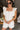 Front view of model wearing the Modern Day Ruffle Romper which features cream fabric, pockets on each side, front zipper closure, square neckline, ruffle straps, elastic band in the back and sleeveless.