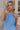 Front view of model wearing the Everly Chambray Blue Halter Neckline Jumpsuit which features light blue lightweight fabric, pleated details, two front slit pockets, wide pant legs, light blue shorts lining, a halter neckline with a twist detail, a sleevel