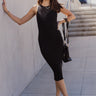 Full body front view of model wearing the Rachel Black Ribbed Sleeveless Midi Dress that features black ribbed knit fabric, midi length, a round neckline and a sleeveless body.
