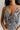 Cloe neckline view of model wearing the All I Want Maxi Dress that has a cream and black floral print, maxi length, a slit on the side, an elastic waist, a halter neckline with cutout details, adjustable straps, and an open back