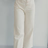 Front view of model wearing the Good Day Pants in Cream that have cream denim fabric, pockets, copper button up closures, belt loops and wide cropped flares.