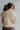 Back view of model wearing the Ready For It Mock Neck Top that has tan cable knit fabric, a cropped waist, one front chest pocket, a mock neck and short sleeves