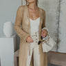 Full body view of model wearing the Speak For Yourself Cardigan which features light taupe open knit fabric, a front tie closure and long sleeves.