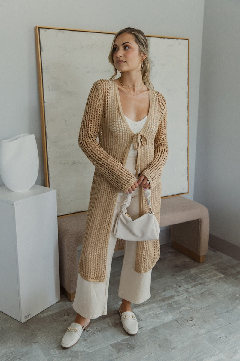 Full body view of model wearing the Speak For Yourself Cardigan which features light taupe open knit fabric, a front tie closure and long sleeves.