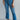 Front view of model wearing the Ceros: Break Even Jeans which features medium blue washed denim, a front zipper with a button closure, belt loops, a high-rise waist, two front pockets, two back pockets, brown stitching and cropped flares.