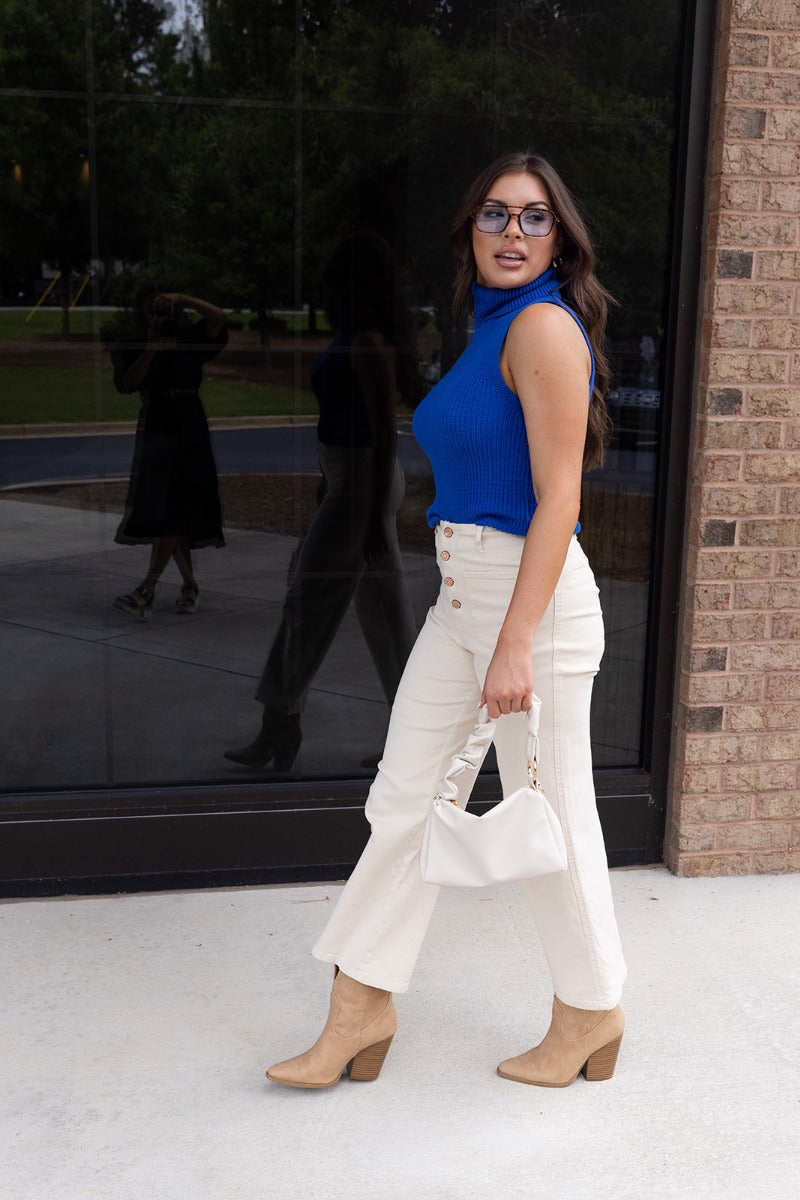 Full body view of model wearing the Rule The World Tank in Blue which features cobalt blue cable knit fabric, a turtle neck neckline, and a sleeveless design.