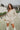 Frontal view of the More Than Enough Romper that features an ivory corduroy material, a collar neck, a surplice front, a long sleeve with a button, a front zipper, pockets, and pleating on the legs
