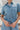 Frontal View of the Heading South Romper that features a blue colored material, a collar neckline, a short cuffed sleeve, a button-up front, two front pockets at the chest, a cinched waist, two side pockets, cuffed bottom hem, and two back pockets.