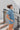 Side View of the Heading South Romper that features a blue colored material, a collar neckline, a short cuffed sleeve, a button-up front, two front pockets at the chest, a cinched waist, two side pockets, cuffed bottom hem, and two back pockets.