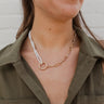The About Time Necklace is a pearl necklace looped through a circle pendant with a gold chain link connected, finished with an adjustable link and clasp closure. 